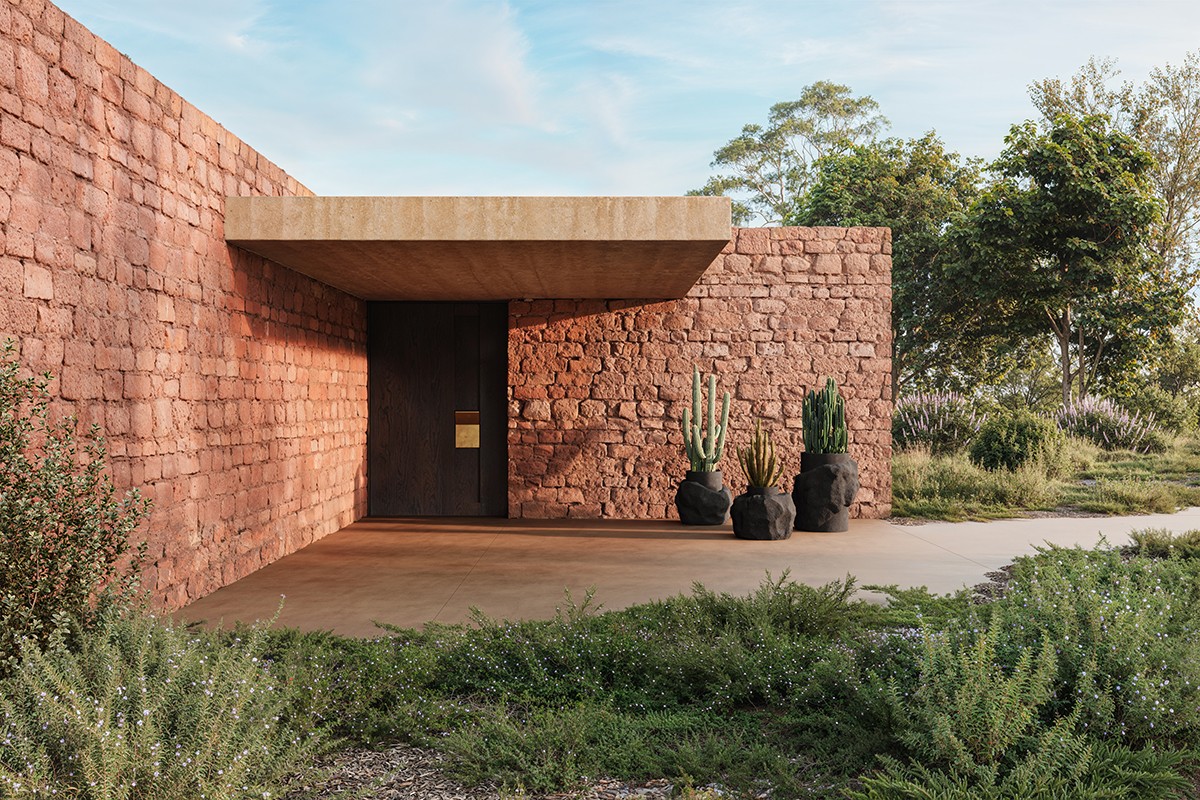 Maison en latérite rouge avec cactus et végétation
